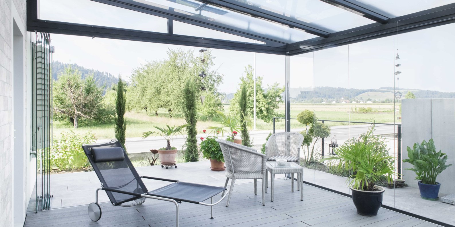 Sommergarten mit ROOFS Glasdach, COVER Verglasung, Liegestuhl und Blick auf Felder