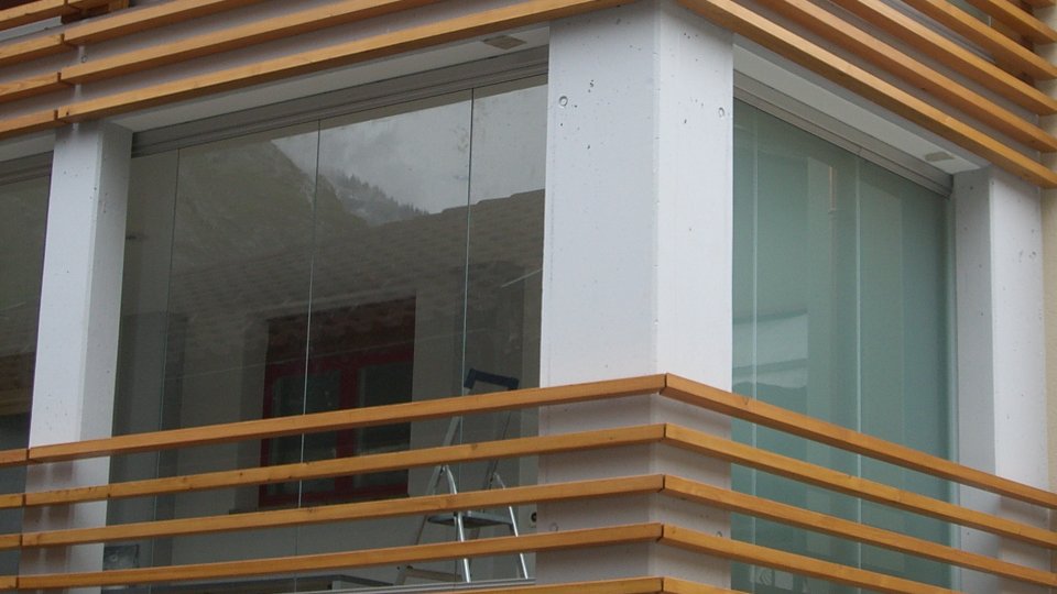 Hausecke mit Holzlamellen-Brüstungen und COVER Balkonverglasung auf zwei Geschossen